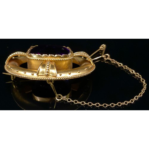 1458 - A Victorian amethyst and gold coloured metal oval brooch in the Etruscan revival manor, the central ... 