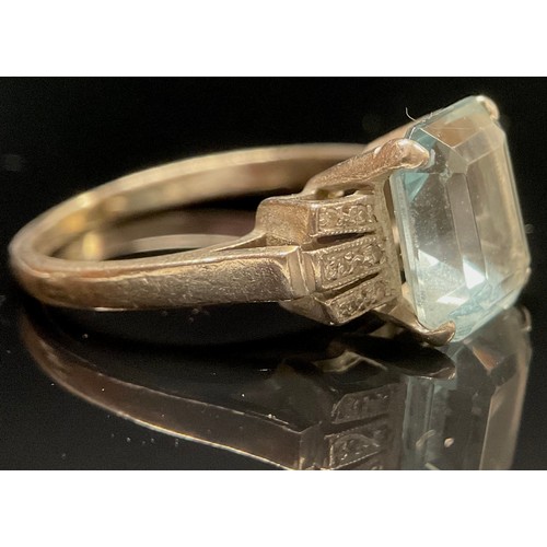 1499 - An Art Deco aquamarine and diamond ring, the central step cut aquamarine claw set within six paneled... 