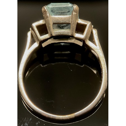 1499 - An Art Deco aquamarine and diamond ring, the central step cut aquamarine claw set within six paneled... 