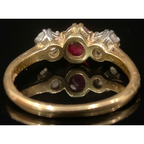 1382 - A diamond, rub and 18ct gold three stone ring, the central ruby flanked by a pair of round brilliant... 