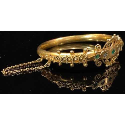 1453 - A Victorian 9ct gold diamond and emerald hinged bangle, the two old brilliant cut diamonds centered ... 