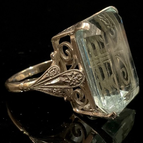 1398 - A large rectangular step cut aquamarine ring, the large stone 22mm high, 12mm wide, the open wirewor... 