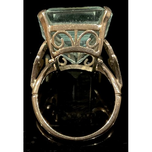 1398 - A large rectangular step cut aquamarine ring, the large stone 22mm high, 12mm wide, the open wirewor... 