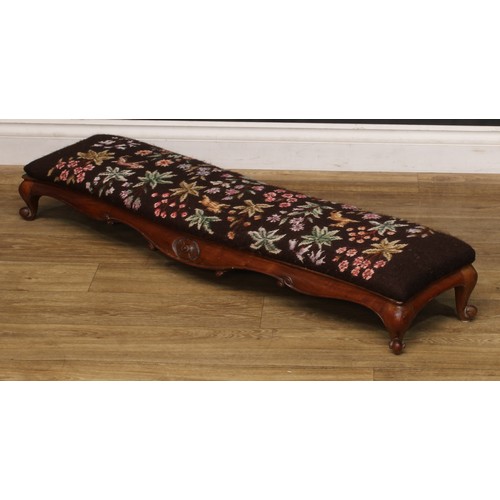 2295 - A Victorian walnut sofa-length serpentine footstool or hearth stool, shaped apron carved with scroll... 