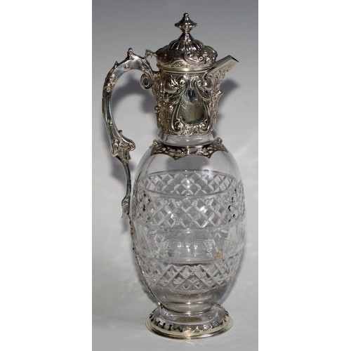 1097 - A Victorian silver ovoid claret jug, hinged cover and mount chased with scrolling leaves and fruitin... 