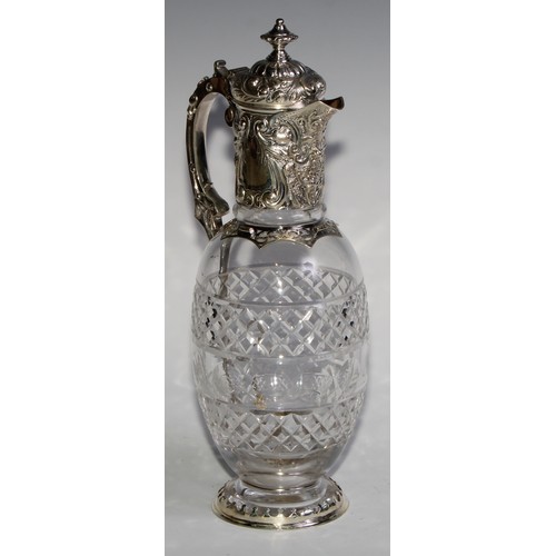 1097 - A Victorian silver ovoid claret jug, hinged cover and mount chased with scrolling leaves and fruitin... 