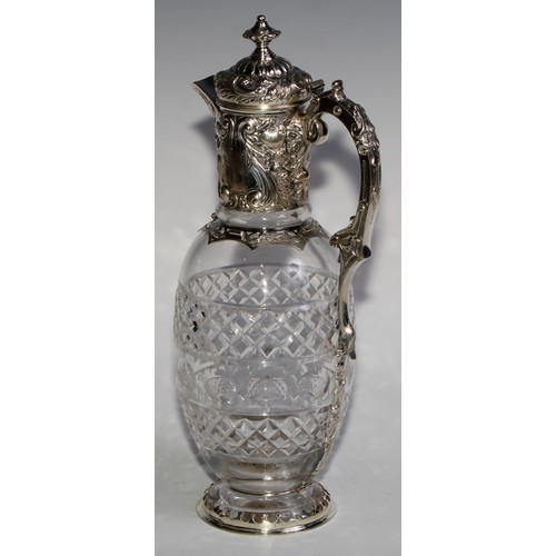 1097 - A Victorian silver ovoid claret jug, hinged cover and mount chased with scrolling leaves and fruitin... 