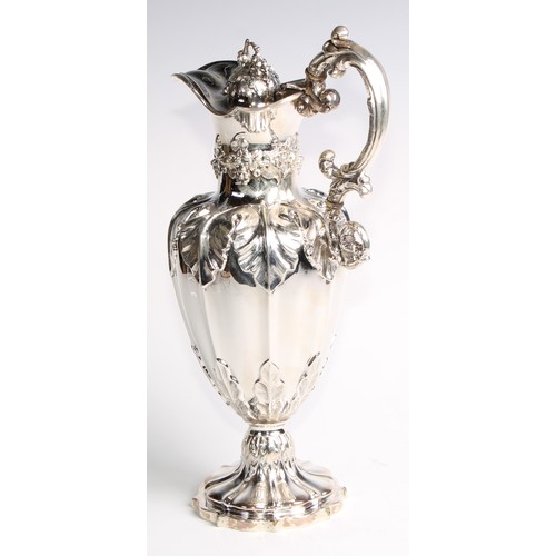 1091 - A Victorian silver fluted pedestal wine ewer, profusely chased with fruiting vine, hinged cover, 32.... 