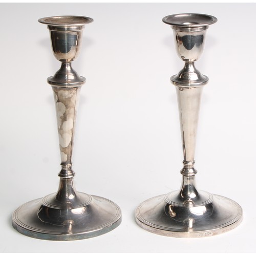 1024 - A pair of Elizabeth II silver table candlesticks, urnular sconces, tapered pillars, circular bases, ... 