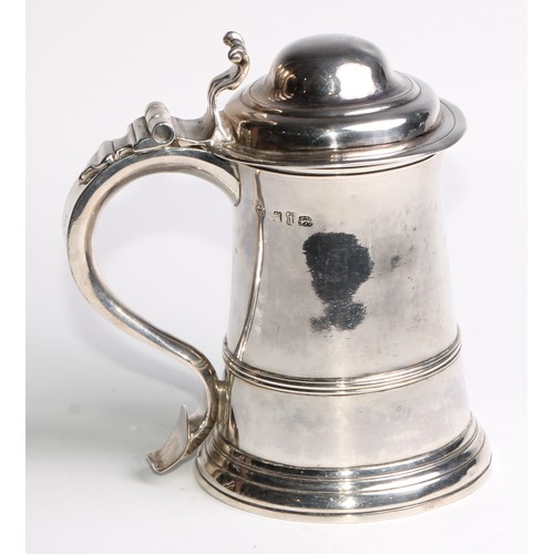 905 - A George II silver spreading cylindrical tankard, hinged domed cover, scroll handle with heart termi... 