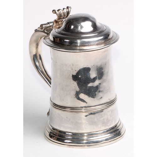 905 - A George II silver spreading cylindrical tankard, hinged domed cover, scroll handle with heart termi... 