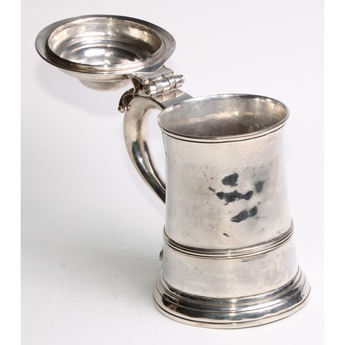 905 - A George II silver spreading cylindrical tankard, hinged domed cover, scroll handle with heart termi... 