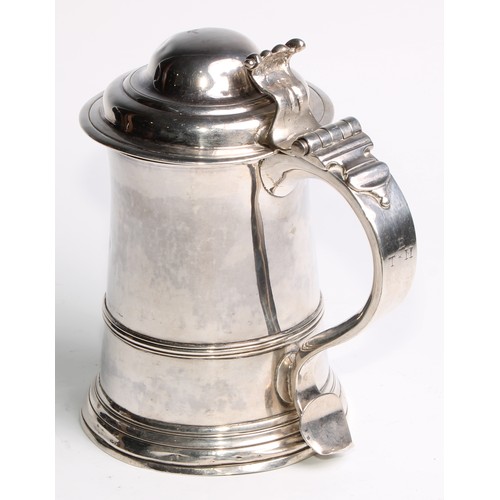 905 - A George II silver spreading cylindrical tankard, hinged domed cover, scroll handle with heart termi... 