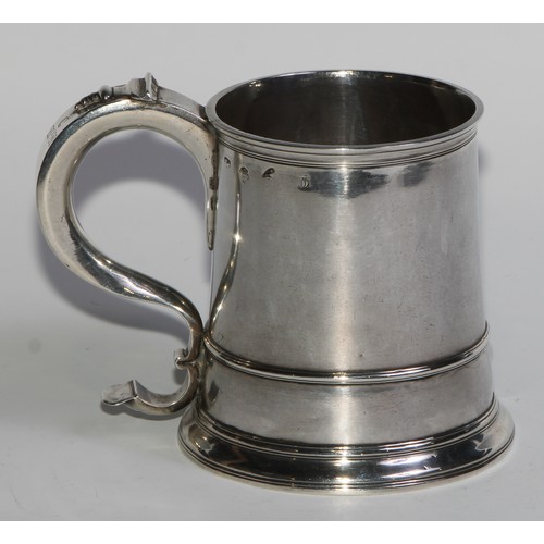 1147 - An early George II silver spreading cylindrical mug, S-scroll handle, three-quarter girdle, skirted ... 