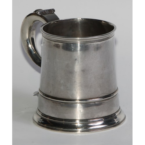 1147 - An early George II silver spreading cylindrical mug, S-scroll handle, three-quarter girdle, skirted ... 