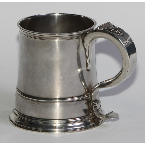 1147 - An early George II silver spreading cylindrical mug, S-scroll handle, three-quarter girdle, skirted ... 