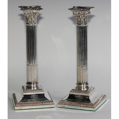 1021 - A pair of Edwardian silver stop-fluted Corinthian column candlesticks, detachable nozzles, gadrooned... 