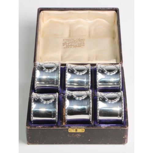 1058 - A set of six George V Neo-Classical Revival silver napkin rings, each numbered, bead-and-reel border... 