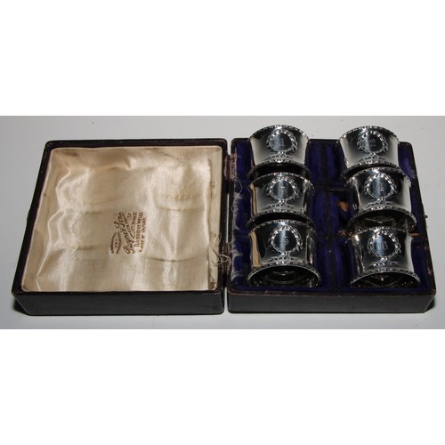 1058 - A set of six George V Neo-Classical Revival silver napkin rings, each numbered, bead-and-reel border... 