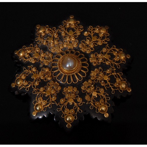 1320 - A 19th century star shaped tortoise shell pique brooch, inlaid with raised leafy gold metal designs,... 