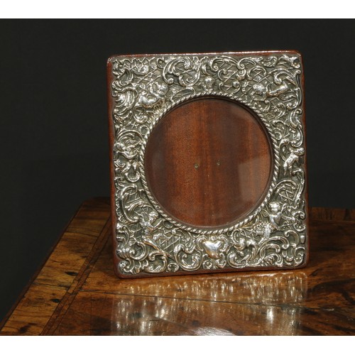 1165 - An Edwardian silver easel photograph frame, embossed with putti and scrolling acanthus, 17cm high, J... 