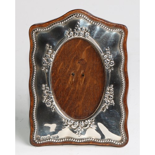 960 - A George V silver easel photograph frame, embossed with flowers, leaves and a beaded border, 12cm hi... 