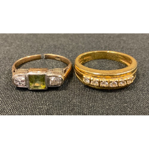 556 - A diamond and green stone dress ring, square cut green stone probably peridot flanked by old irregul... 