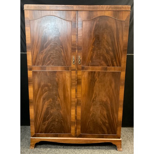 38 - A mid century reproduction mahogany wardrobe, pair of doors enclosing five tiers of shelving to one ... 