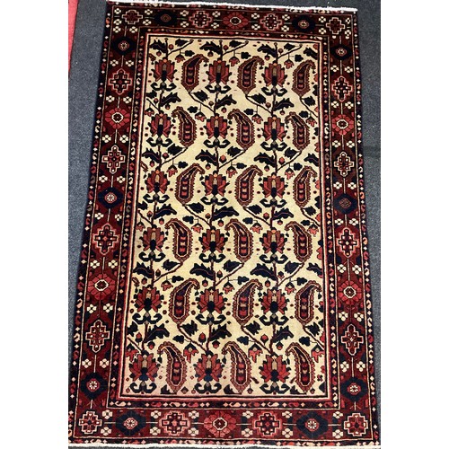 98 - A Central Persian Bakhtiar rug / carpet, hand-knotted in deep red, indigo, and brown, on a cream gro... 