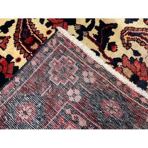 98 - A Central Persian Bakhtiar rug / carpet, hand-knotted in deep red, indigo, and brown, on a cream gro... 