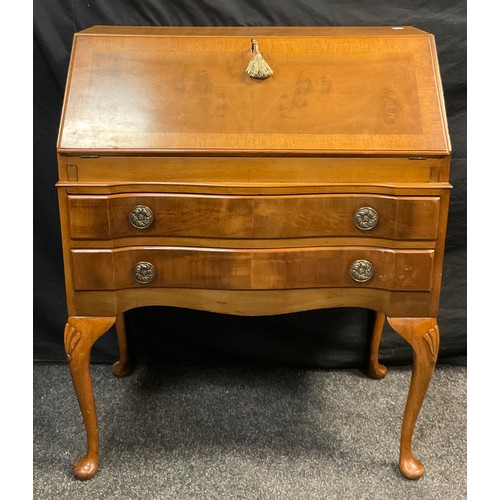 113 - A reproduction walnut bureau, serpentine shaped front, hinged fall door to top enclosing a fitted in... 