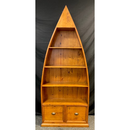 157 - A stained pine boat-shaped open bookcase, three tiers of shelving above a pair of deep drawers, (as ... 