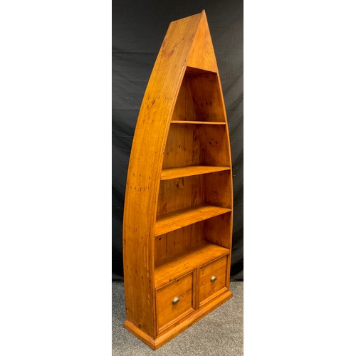 157 - A stained pine boat-shaped open bookcase, three tiers of shelving above a pair of deep drawers, (as ... 