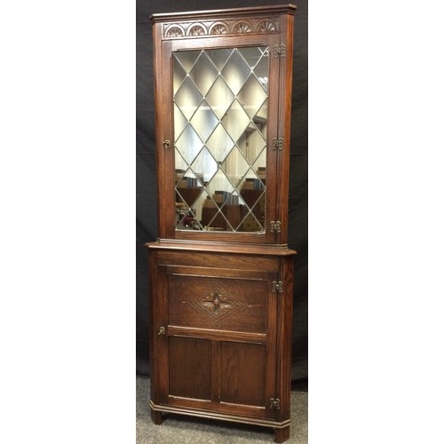 166 - A Jaycee oak floor-standing corner cabinet, moulded cornice, carved frieze, leaded glass to top door... 