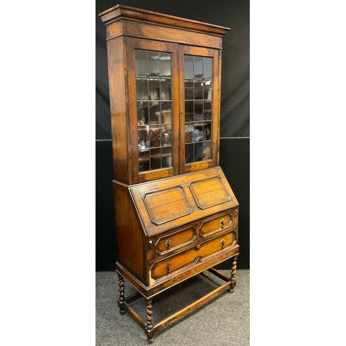 455 - An early 20th century oak bureau bookcase, out swept cornice above a pair of glazed leaded doors wit... 