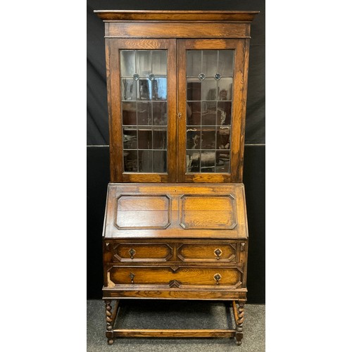 455 - An early 20th century oak bureau bookcase, out swept cornice above a pair of glazed leaded doors wit... 