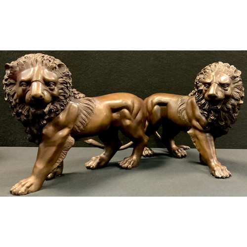 472 - A pair of bronzed metal figures of lions, 33cm long