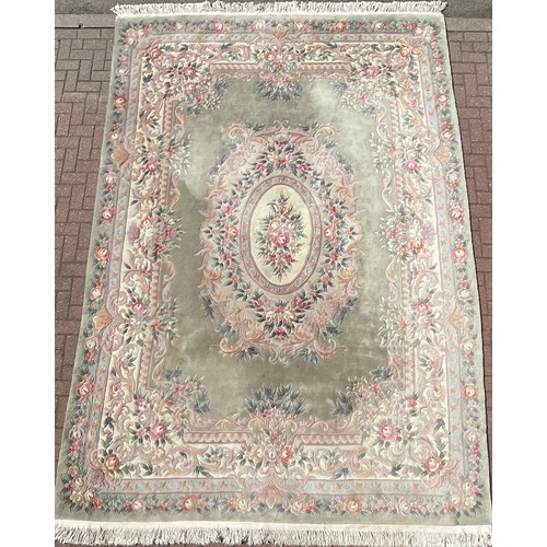 477 - A large Chinese woollen rug, with sculpted flower and foliage decoration, in tones of jade green, pi... 