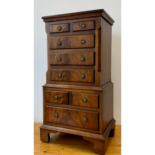 415 - A George III style mahogany bedside cabinet in the form of a chest on chest, over-sailing top above ... 