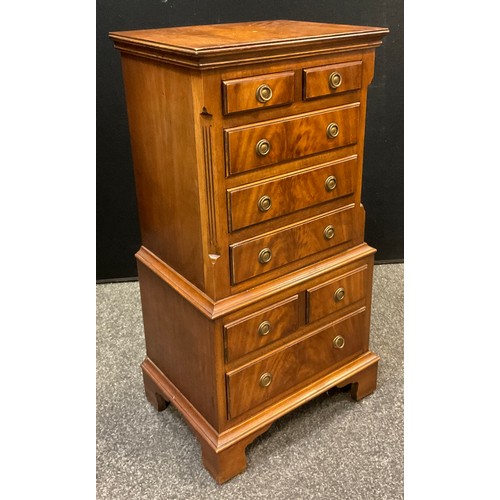 415 - A George III style mahogany bedside cabinet in the form of a chest on chest, over-sailing top above ... 