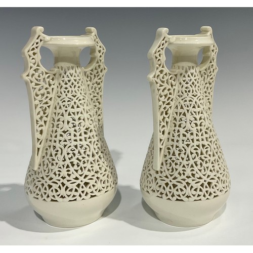21 - A pair of Graingers Worcester reticulated spreading ovoid vases, in the white, with Persian inspired... 