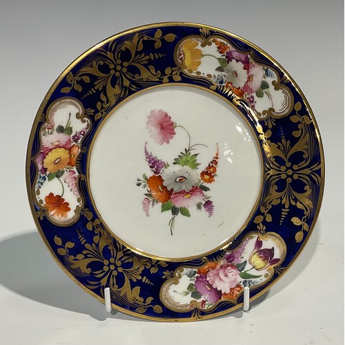 132 - An English porcelain shaped circular plate, the field painted with a basket of flowers and fruit on ... 
