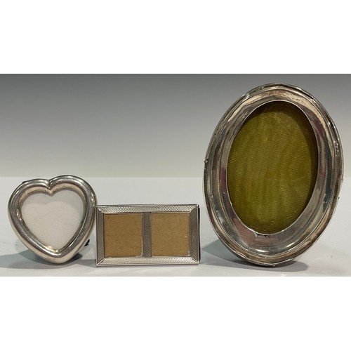 151 - A silver oval photograph frame, Birmingham 1909; another, heart shaped, marked 925; a miniature doub... 