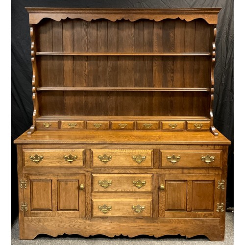 A George III style country kitchen oak dresser, shaped cornice, three ...