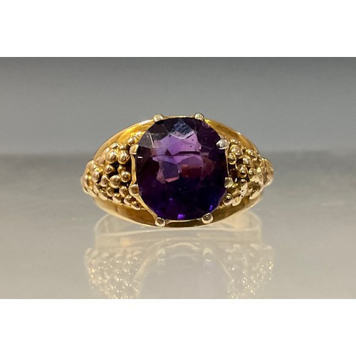 91 - A 20th century amethyst ring, oval amethyst crown claw set above textured shoulders, yellow metal sh... 