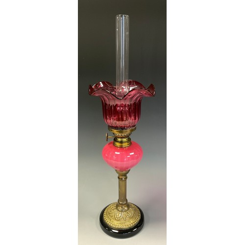 680 - A Victorian style brass and cranberry glass oil lamp of small proportions, shaped shade. milk cranbe... 