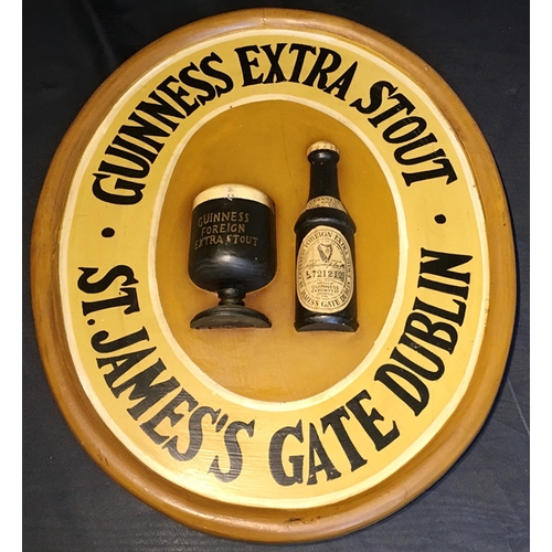 12 - Advertising and Breweriana - an oval wooden Guinness wall plaque with Guinness glass and bottle deco... 