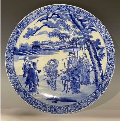 13 - A large 19th century Chinese circular charger, decorated in underglaze blue with musicians at river ... 