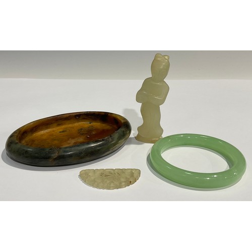 99 - A Chinese hardstone oval dish, 12.5cm wide; a jade figure, 8.5cm high; a bangle; a fan shaped carvin... 