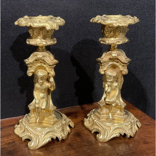 329 - A pair of French Rococo style gilt bronze candlesticks, each stem with seated putti within sculpture... 